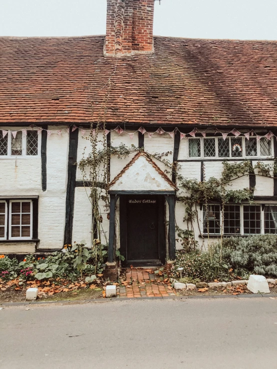 a building with windows, plants, and flowers growing around the house