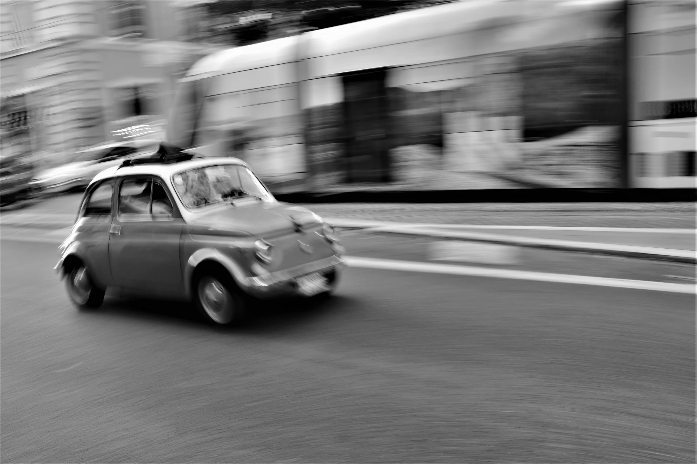 a black and white image of an old - school styled car moving on the road