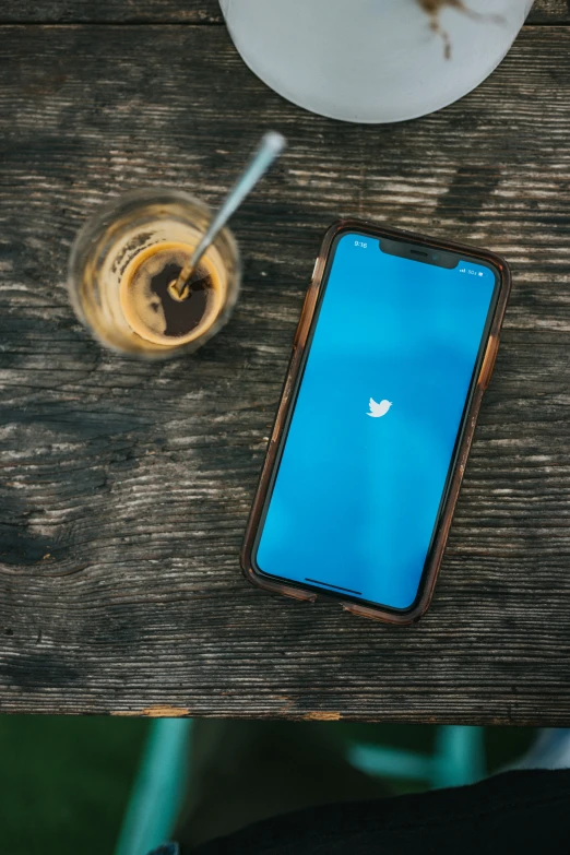 an iphone is laying on the table next to a drink