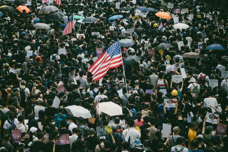 a large group of people with american flags and umbrellas