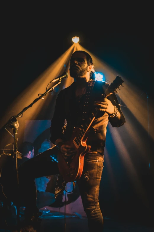 a man holding onto a guitar playing on stage