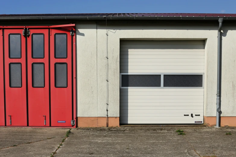 two garage doors are open beside a garage with white wall and tan stucco