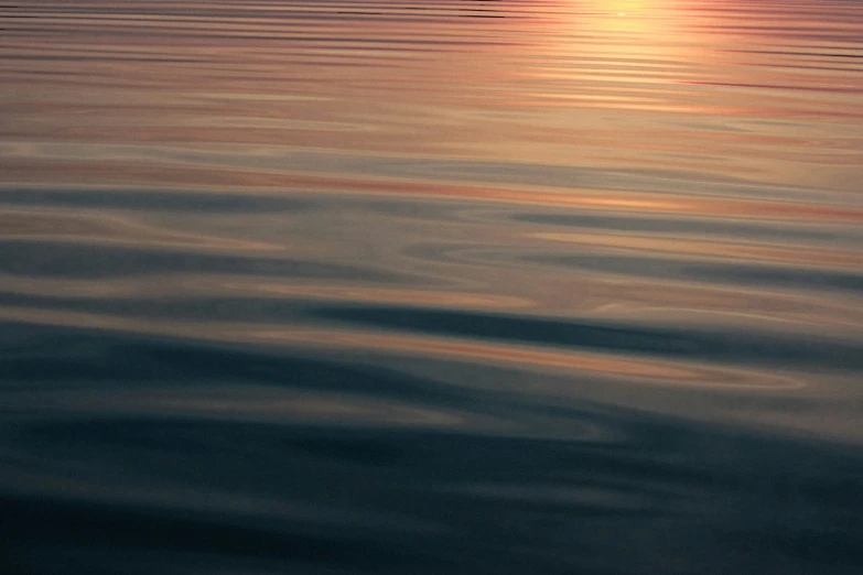 the sun setting over the ocean with the boat in the distance