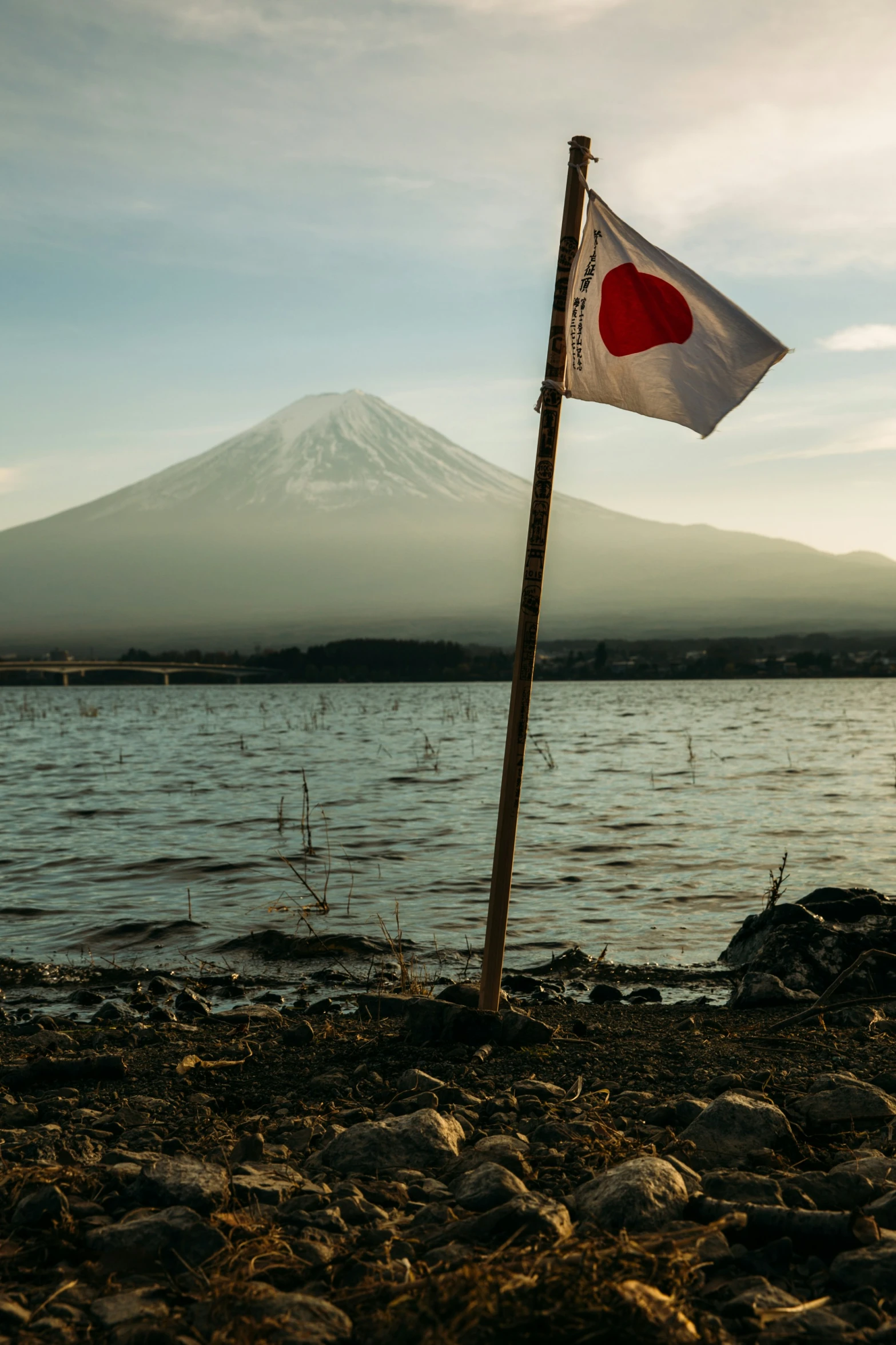 a japanese flag on the shore of a lake