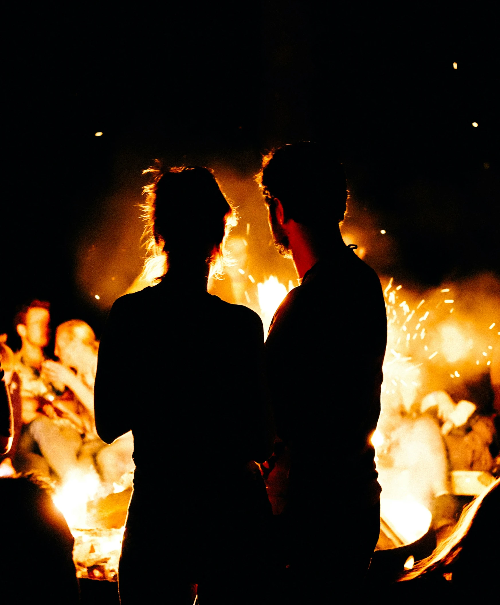 two people facing each other in front of a lot of fire
