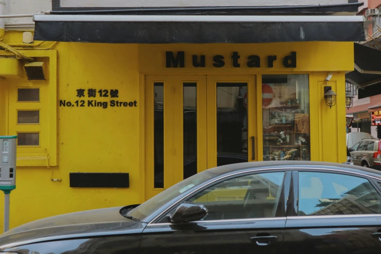 there is a car parked in front of the mustard yellow building