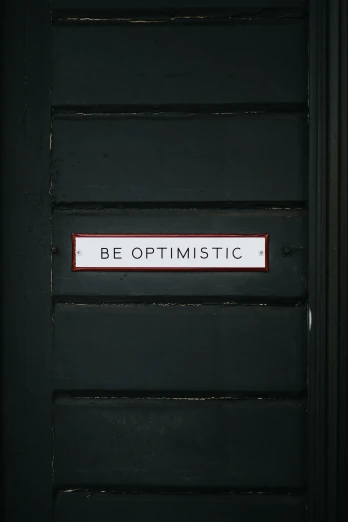 the door with a red trim and sign that says be optimistic