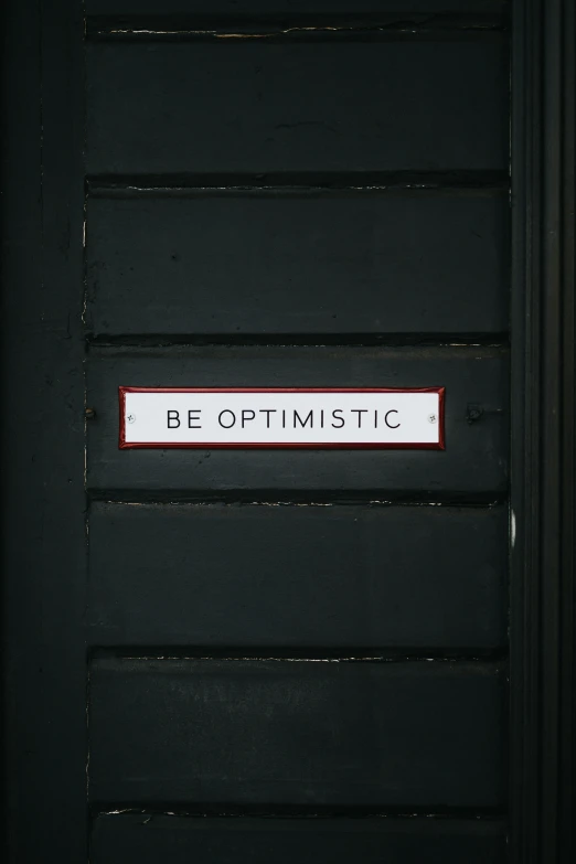 the door with a red trim and sign that says be optimistic