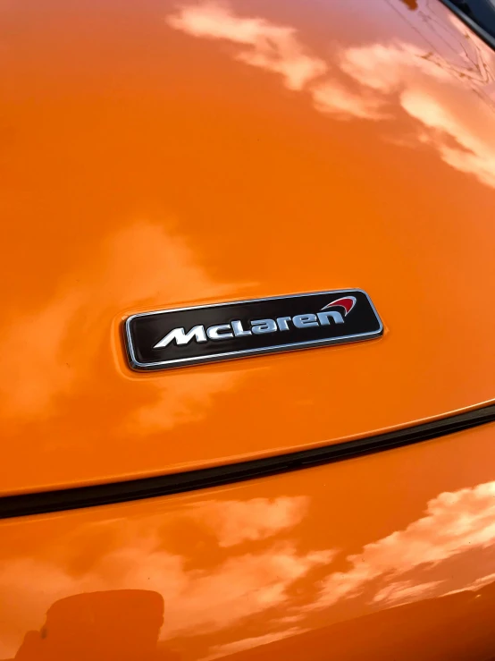 the front end of an orange car with a logo