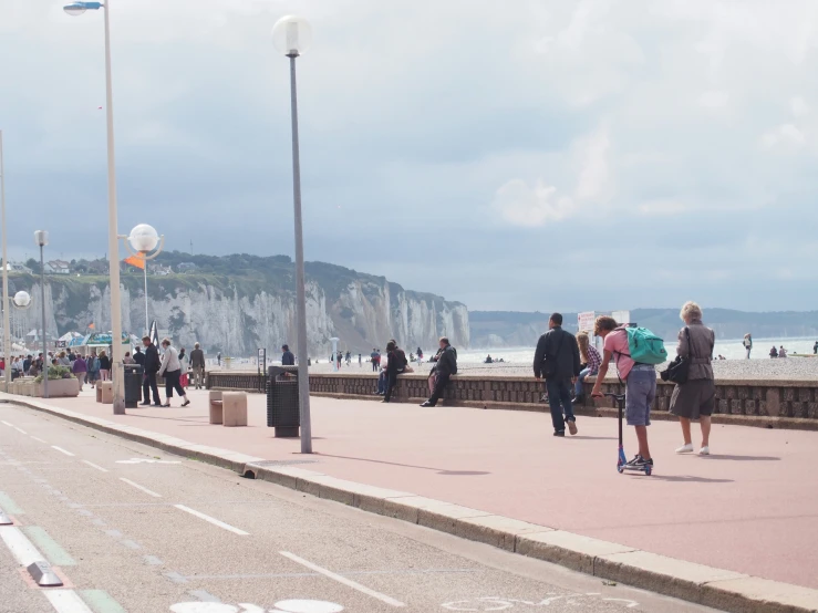 people walking on a beach promenade along the water