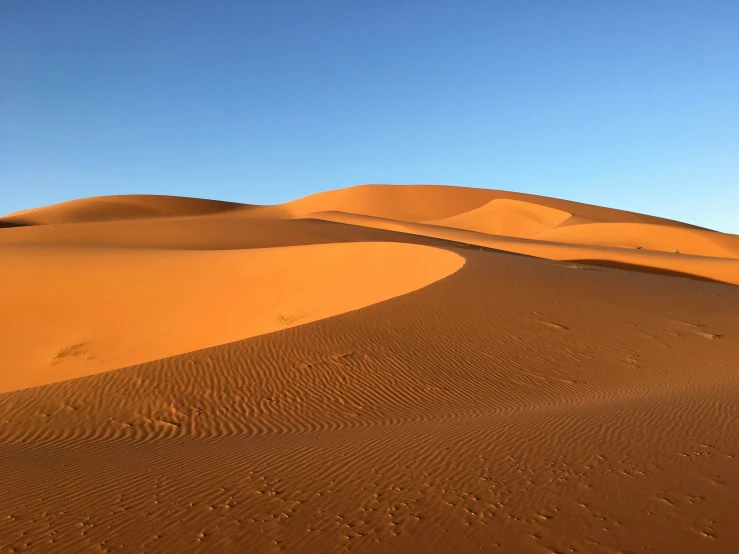 a desert landscape with two people hiking through the sand