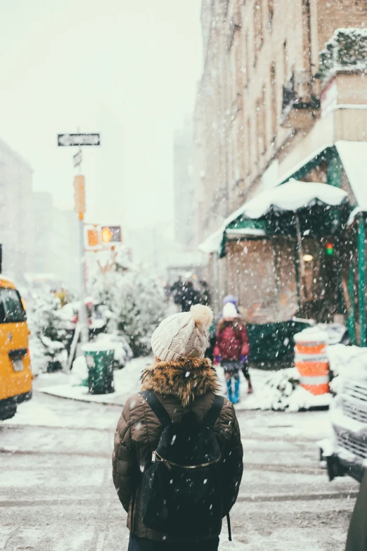 a person standing in the street with snow falling on them