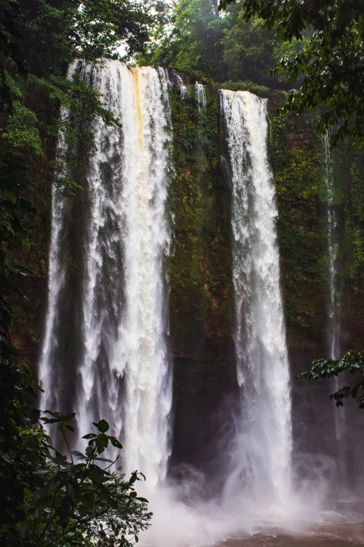 a group of large waterfalls surrounded by lush green trees