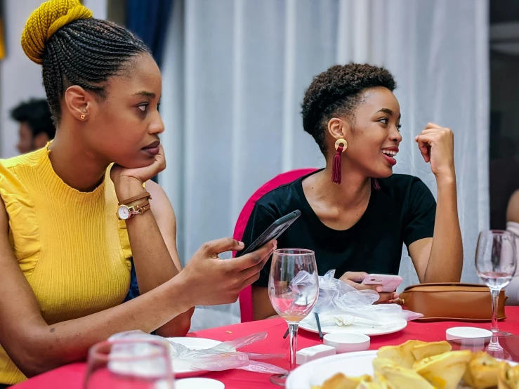 two women are sitting together at a table having an interaction