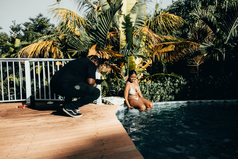 a person sitting next to a swimming pool and another standing up