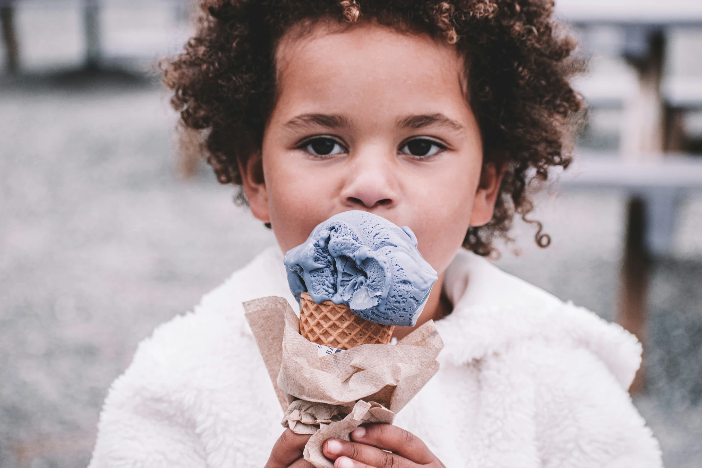 a little girl holding a blue ice cream cone in her hand