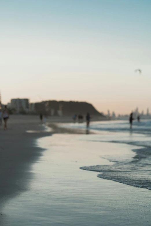 a bunch of people walking along a beach by the ocean