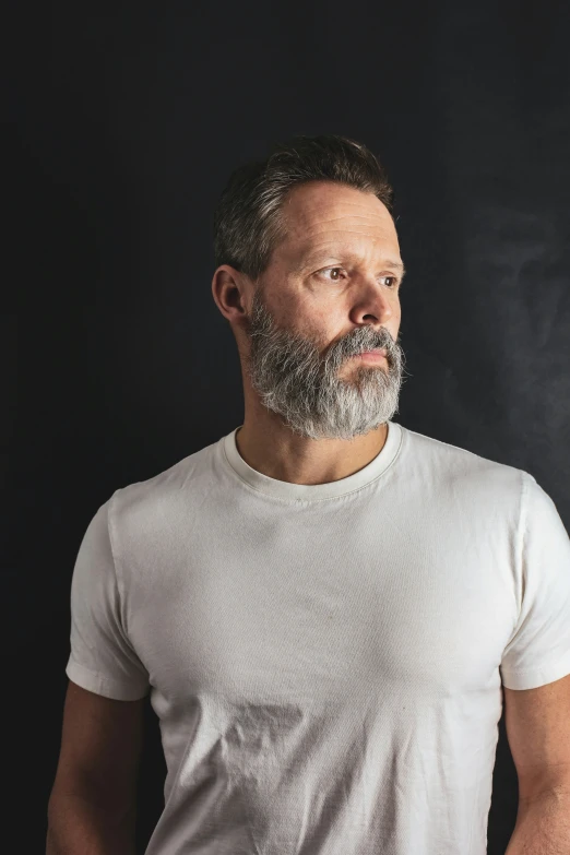 an older man wearing a white shirt looking back with a concerned expression