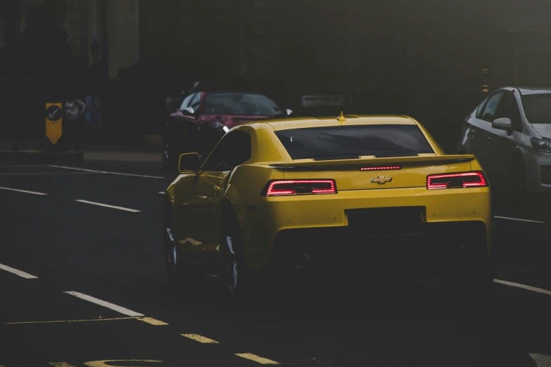 the rear of a yellow car on a city street