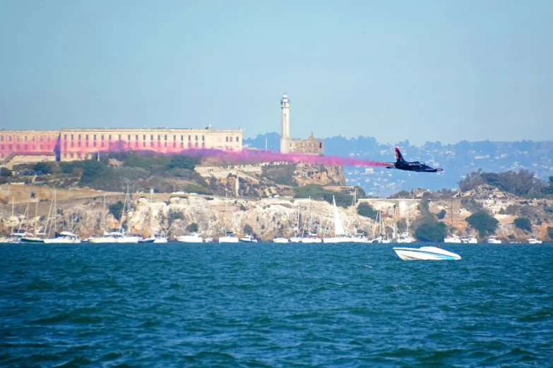 jet fighter jets flying over the water in front of a city