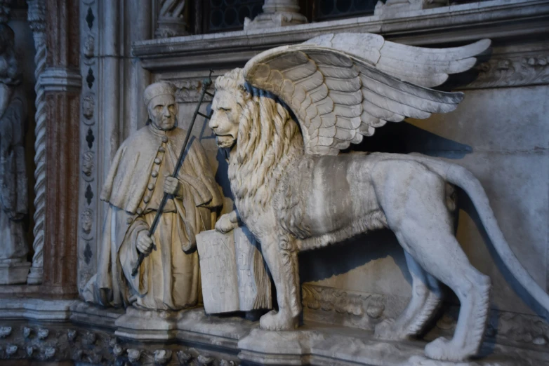 sculptures of lions and men stand on a pedestal