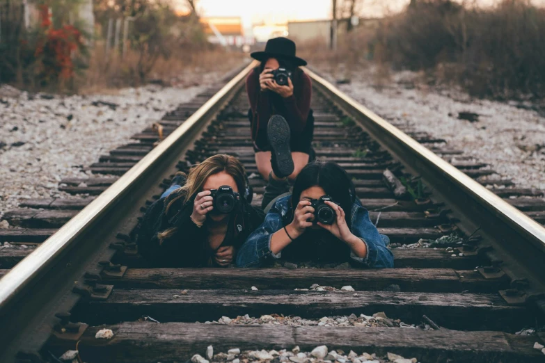 two women sitting on train tracks taking pos