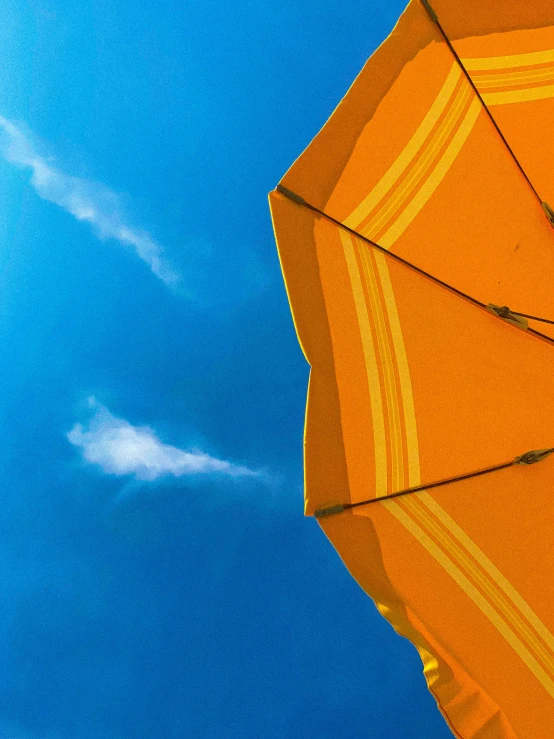 two orange umbrellas are open in front of the sun