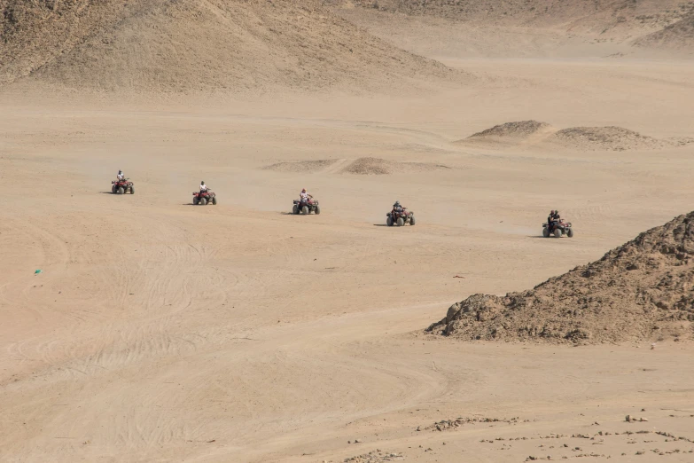 four people riding bikes down a sandy terrain