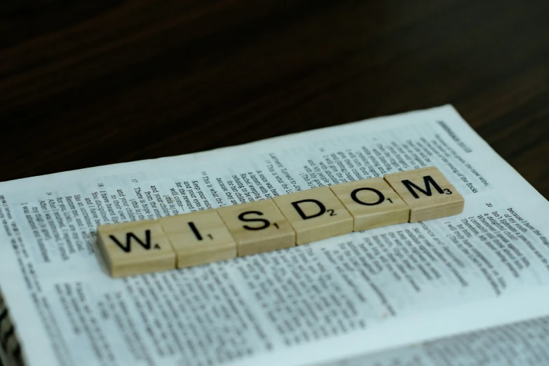 a close up of an open book with the word wisdom spelled in scrabble