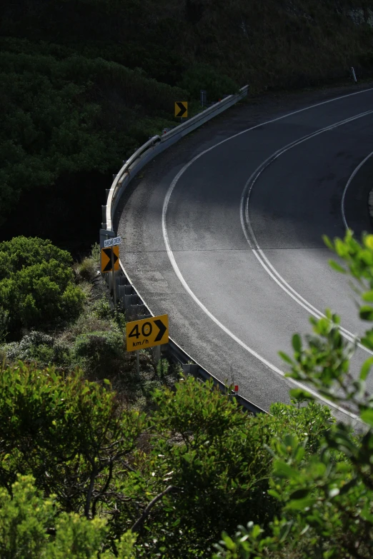 a curve in the road with speed limit sign below