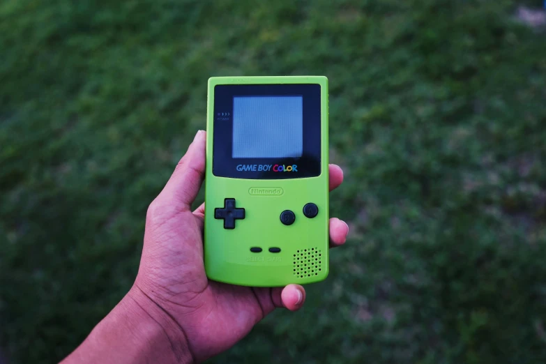 a person holding a small game boy in their hand