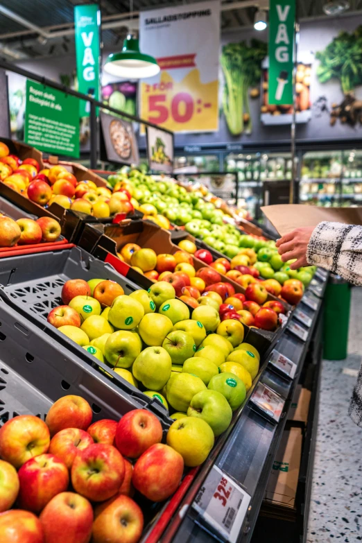 a person picking apples in an open produce market