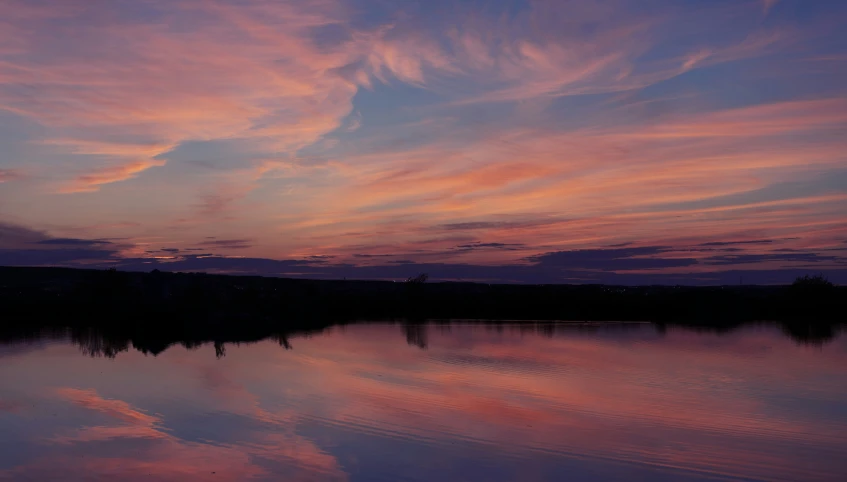 a calm body of water is in the distance as clouds and blue skies reflect in the surface