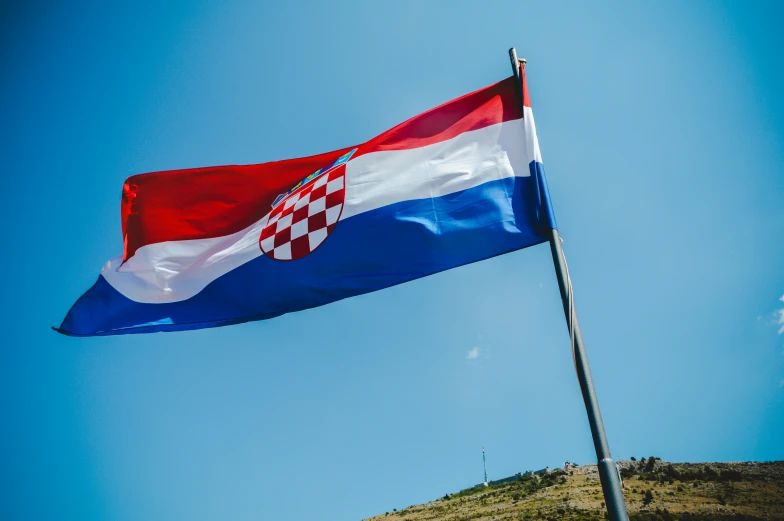 the danish flag flies in the air near some grass