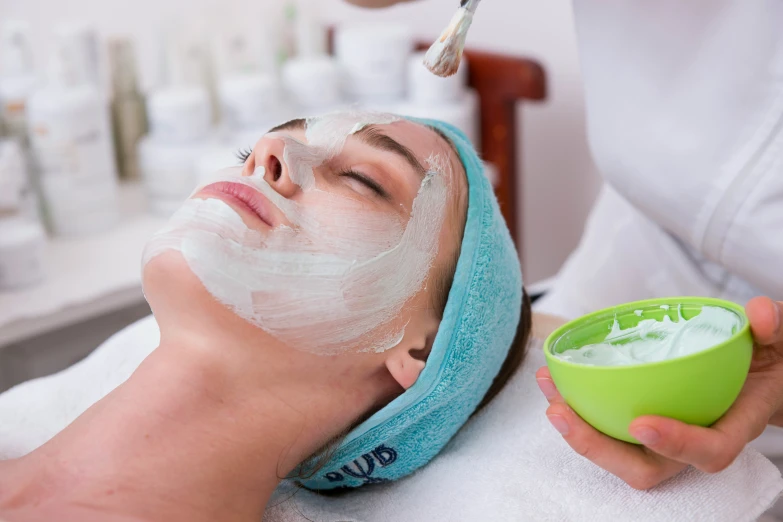 a woman getting a facial mask at the spa