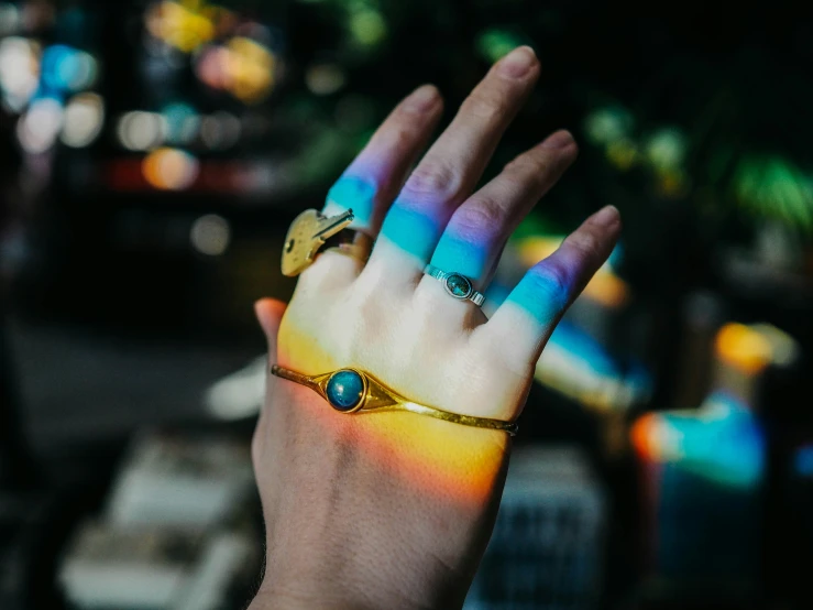 the person's hand is holding a brightly colored ring