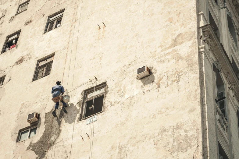 two men are on a ledge next to windows