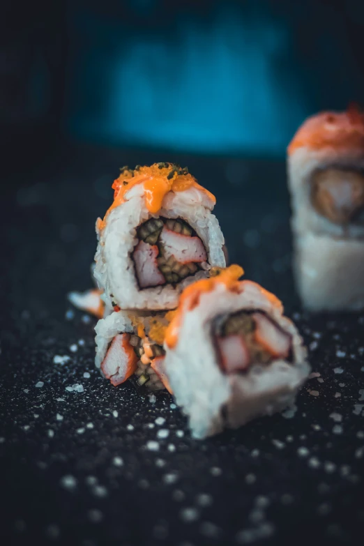 three sushi rolls sit on a counter with meat and vegetables