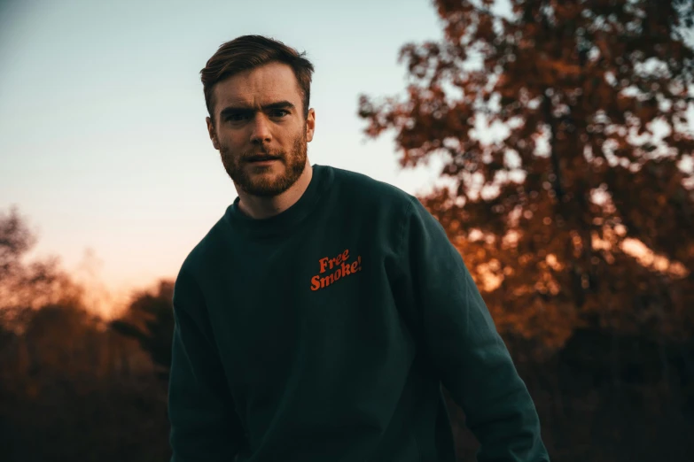 a man standing in a park in a sweatshirt