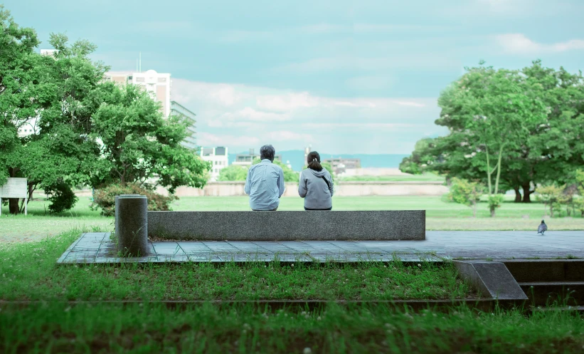 a couple sitting on a park bench, one taking a picture