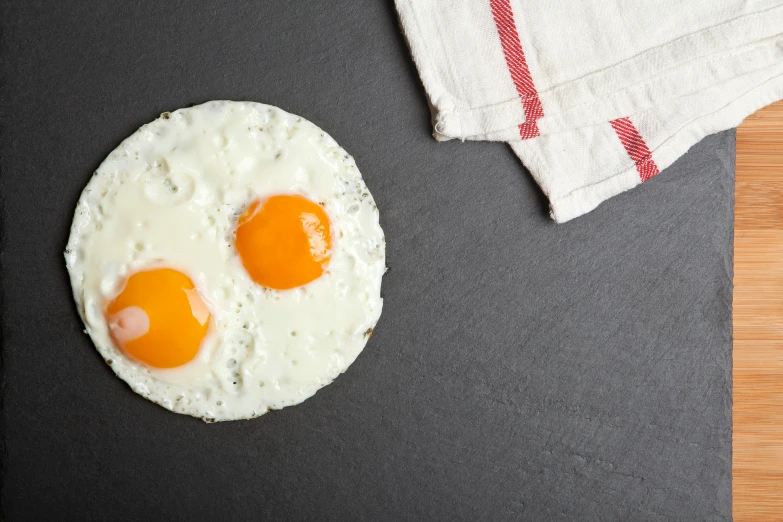 two eggs and a cloth on a black counter