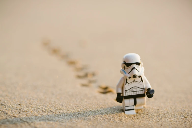 small toy figurine wearing a helmet and sunglasses standing in the sand