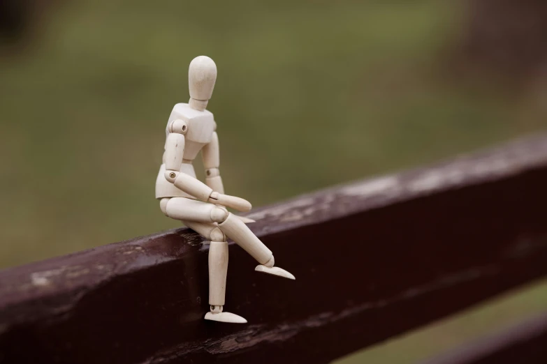 a wooden mannequin sitting on top of a brown bench