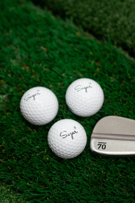 three golf balls next to a wedge and a driver's golf club