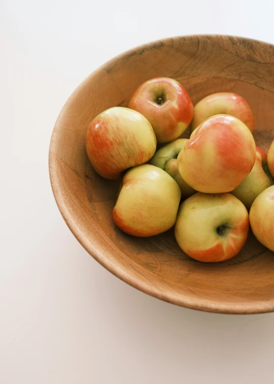 a wooden bowl filled with nine apples