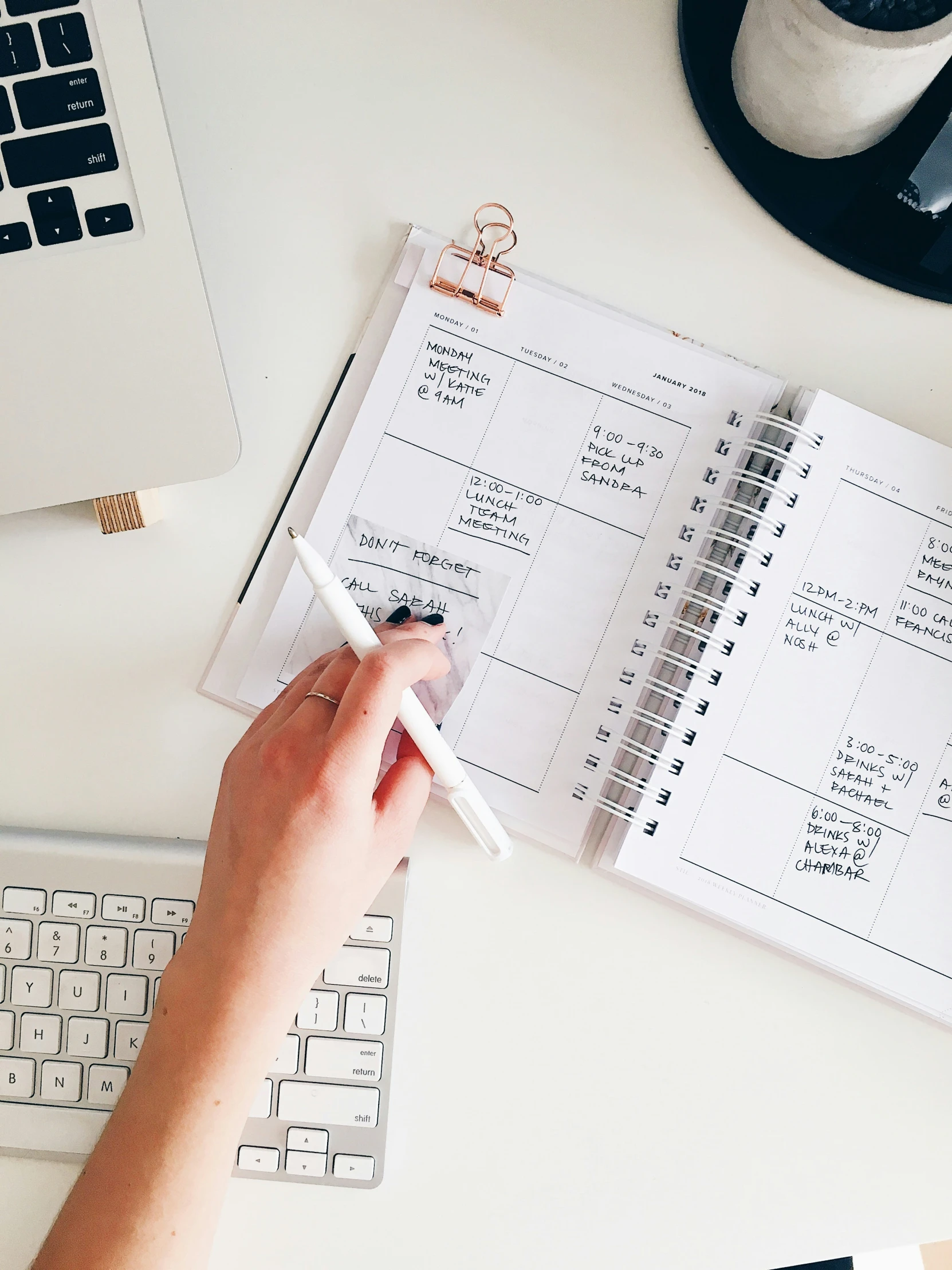 a hand with a pen is holding a planner