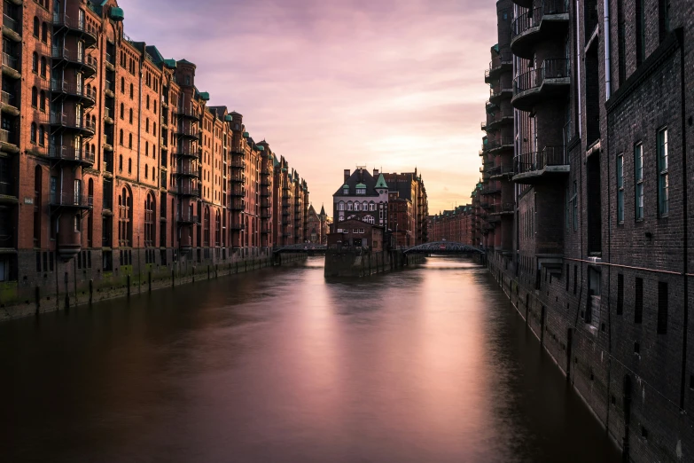 a canal lined with large brick buildings near a bridge