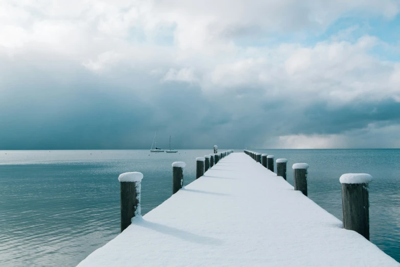 a snow covered pier sitting on top of a blue ocean