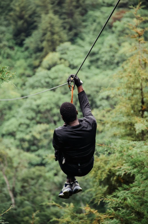 the man is zipping through the trees with his feet dangling over