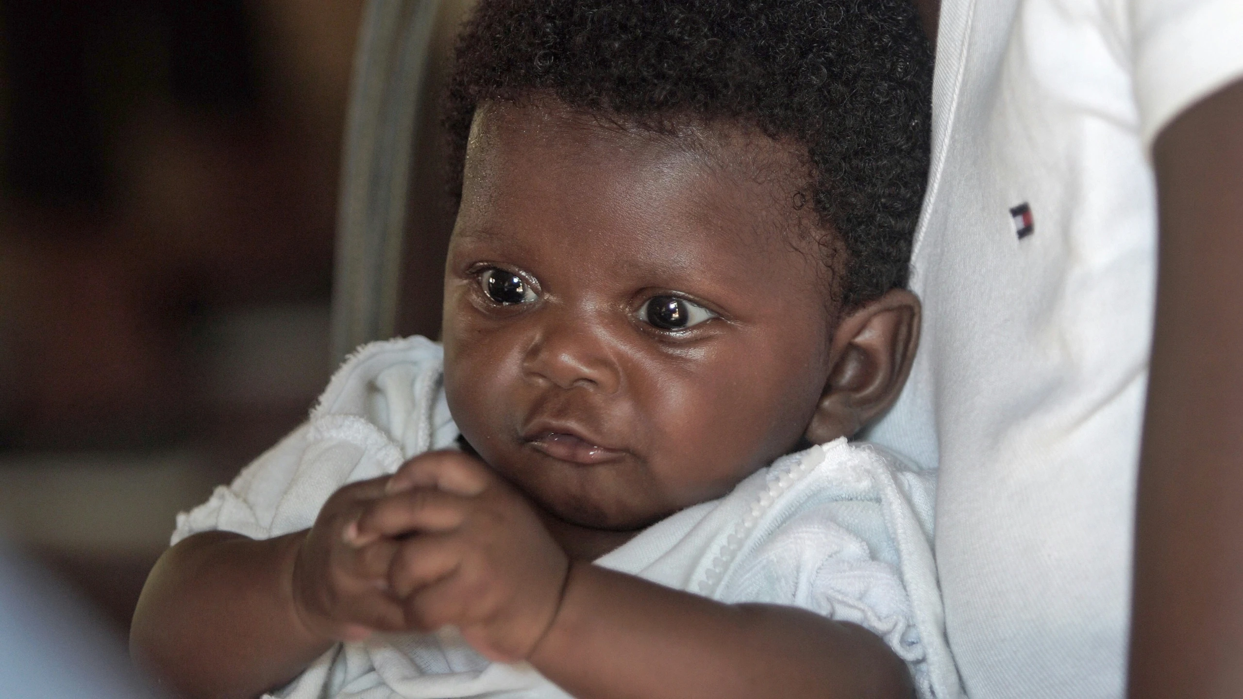 a baby looking directly at the camera in her mother's arms